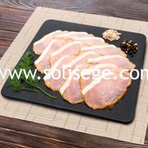 12 slices of smoked back bacon laid out nicely on a black square tile board.