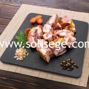 Chunks of Solisege bacon bone on a black square tile board.