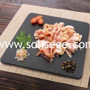 Raw Solisege baocn chips on a black square tile plate.