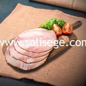4 slices of Solisege baked ham on a wooden board with lettuce, tomatoes, and rock salt as garnish.