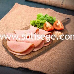 6 slices of Solisege Canadian Ham on a wooden board with lettuce and tomatoes as garnish.